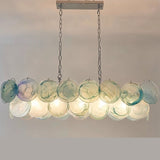"A modern, rectangular chandelier with cascading green and iridescent glass discs, illuminated and suspended by chains."