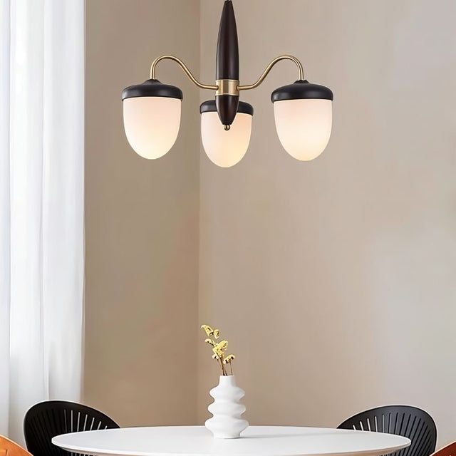 "A 3-light chandelier with brass arms, wooden centerpiece, and frosted glass shades over a dining table."