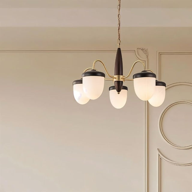 "A 5-light chandelier with brass arms, wooden centerpiece, and frosted glass shades in an interior design setting."