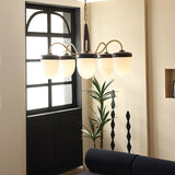 "A chandelier with brass arms, wooden centerpiece, and frosted glass shades in a living space."