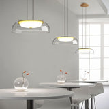 "Three modern pendant lights with clear glass dome shades, hanging above white dining tables with glass vases and flowers."