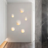 "Multiple white gypsum Onexa trimless wall lights with dome-like profiles, casting ambient light in a modern hallway."