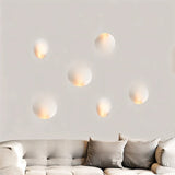 "Multiple white gypsum Onexa trimless wall lights with dome-like profiles, casting ambient light on a wall above a sofa."