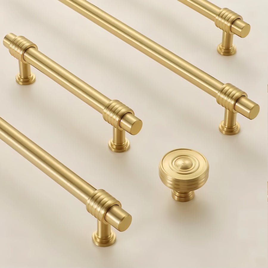 "set of brass knobs and pull bars displayed on light surface"
