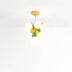 Whimsical pendant chandelier with brass finish, white frosted globe shades, and colorful yellow and green floral accents.
