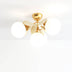 Gold brass chandelier with cream petal arms and three frosted white globe lights against a white background.