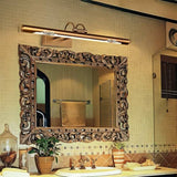 "A copper LED vanity light with decorative cutouts mounted above an ornate, carved bathroom mirror."