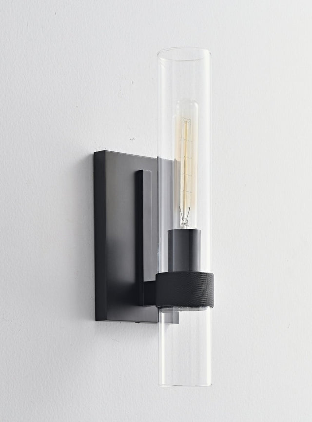 "A modern black wall lamp with a cylindrical glass shade, blending vintage and contemporary styles with a sleek, warm glow."
