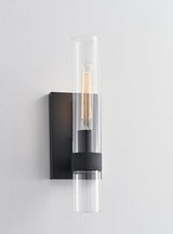 "A modern black wall lamp with a cylindrical glass shade, blending vintage and contemporary styles with a sleek, warm glow."