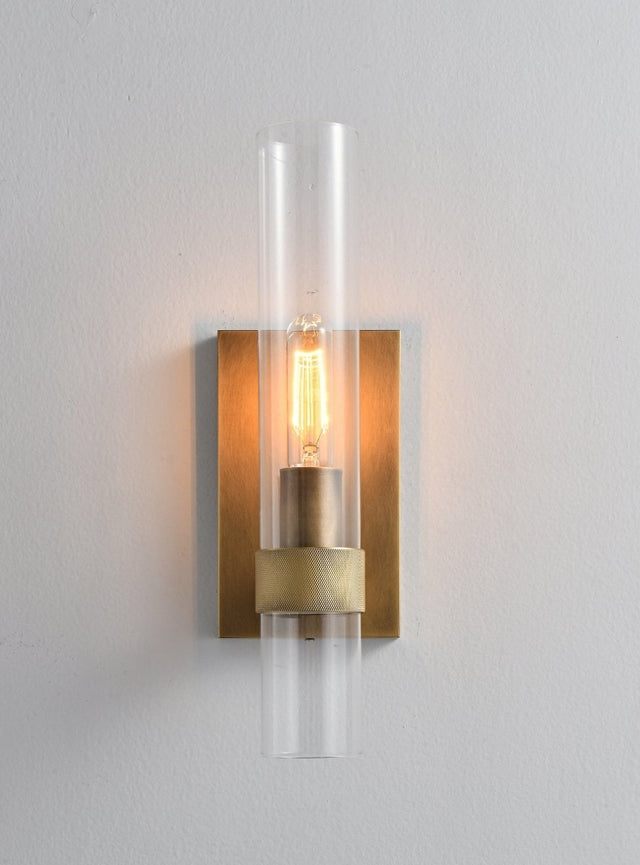 "A modern brass wall lamp with a cylindrical glass shade, blending vintage and contemporary styles with a bronze finish and black accents."
