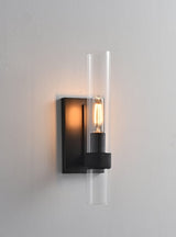"A modern black wall lamp with a cylindrical glass shade, blending vintage and contemporary styles with a sleek, warm glow."