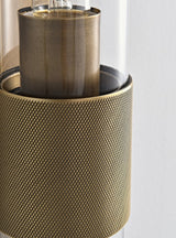 "Close-up detail of a modern brass wall lamp with a cylindrical glass shade, showcasing its intricate design and texture."