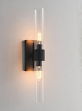 "A modern brass wall lamp with a long, vertical cylindrical glass shade, showcasing a bronze finish with black accents, blending vintage and contemporary styles."