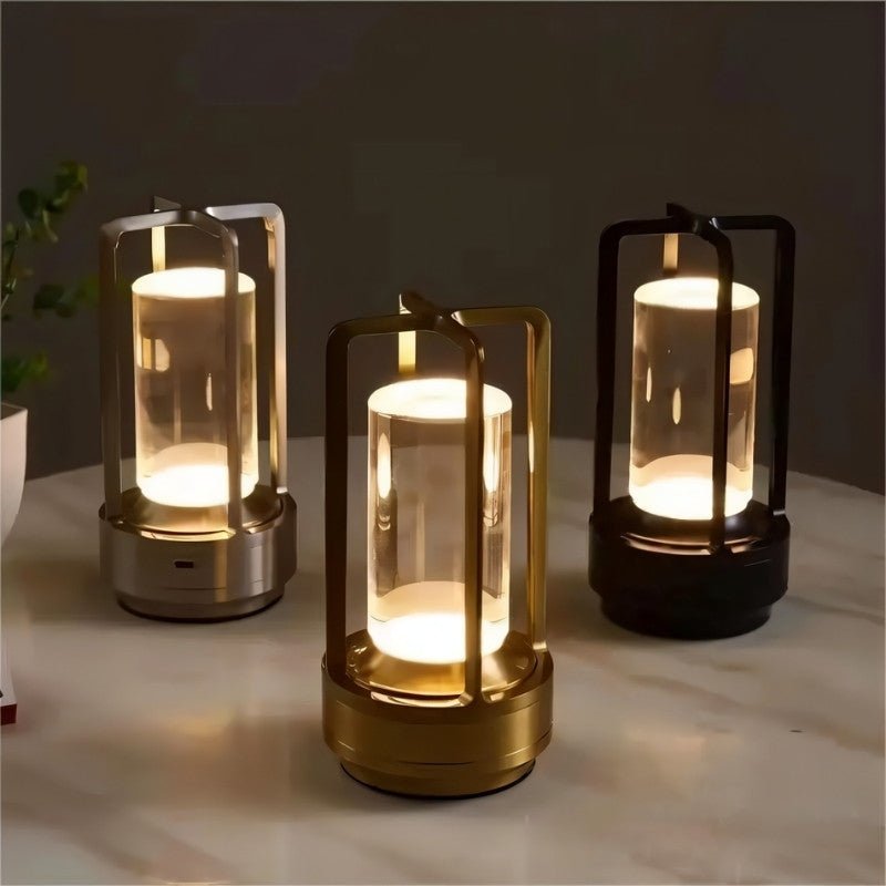 Orena Table Lamp - Sleek Rechargeable Indoor/Outdoor Light in black, gold, and silver finishes, glowing brightly on a marble tabletop.