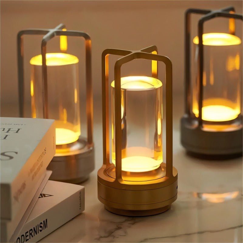 Orena Table Lamp - Sleek Rechargeable Indoor/Outdoor Light in gold and black finishes, glowing warmly on a marble surface for cozy decor.