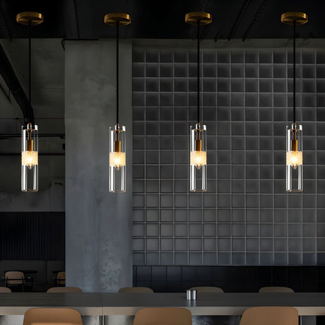 "Four modern pendant lights with clear textured glass shades hanging over a kitchen island."