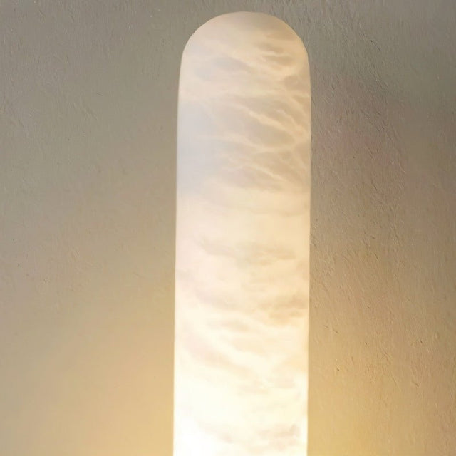 "Alabaster shade of a modern vertical wall lamp emitting a soft, warm light."