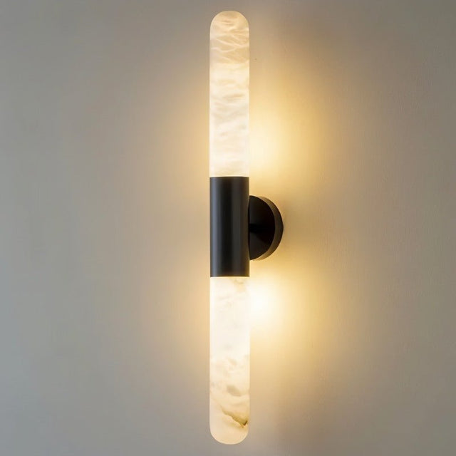 "Modern vertical wall lamp with a black metallic center and cylindrical alabaster shades emitting soft light."