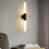 "Modern alabaster wall lamp with a black metallic center, illuminating a contemporary bedroom."