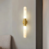 "Modern wall lamp with a gold metallic center and a cylindrical alabaster shade, emitting soft light."