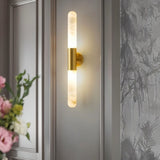 "Modern gold and alabaster wall lamp illuminating a contemporary living room with soft, ambient light."