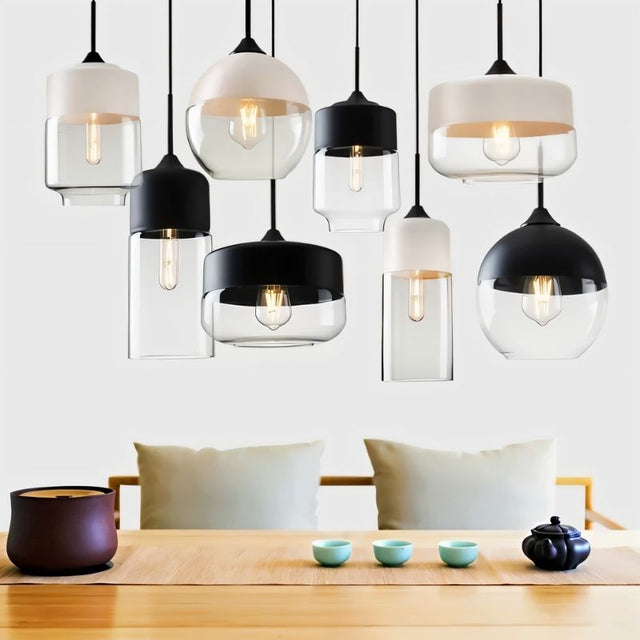 "A collection of modern pendant lights with various shapes and glass shades hanging above a dining table."