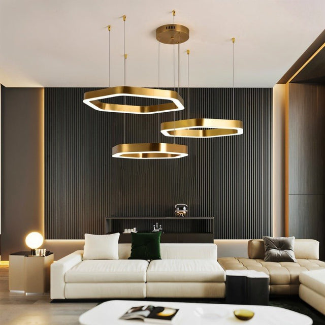 "A modern, gold geometric chandelier hangs in a stylish living room with a dark accent wall."