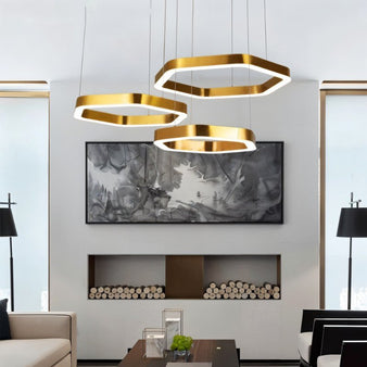 "A modern, gold geometric chandelier hangs above a contemporary living room with a fireplace."