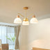 Modern three-light pendant chandelier with brass arms and frosted white glass shades