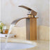Waterfall bathroom faucet with antique bronze finish and wooden base mounted on white sink.