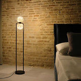 "Floor lamp with an alabaster globe emitting soft, diffused ambient light, perfectly complementing the bedroom setting with a minimalist aluminum frame."