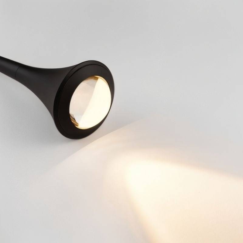 Close-up of the black Osvet Pendant Light casting a warm, focused beam of light on a white surface.