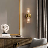 "A modern brass wall lamp with textured glass shades illuminating a living room."