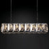 Linear chandelier with brushed nickel finish and geometric crystal panels, suspended against a black background.