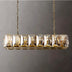 Gold linear chandelier with clear crystal panels and chain suspension against a gray background.
