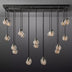 Linear chandelier with black metal frame and 12 ribbed glass globe pendants in warm amber tones, suspended against a gray background.