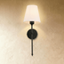 Two modern wall sconces with tapered linen shades and circular backplates shown front and side view with dimensions on white