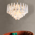 White alabaster teardrop chandelier with brass accents hanging above a rust-colored sofa against a gray wall.