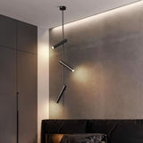 "A modern black stainless steel pendant light with adjustable tubes in a bedroom with a dark headboard."