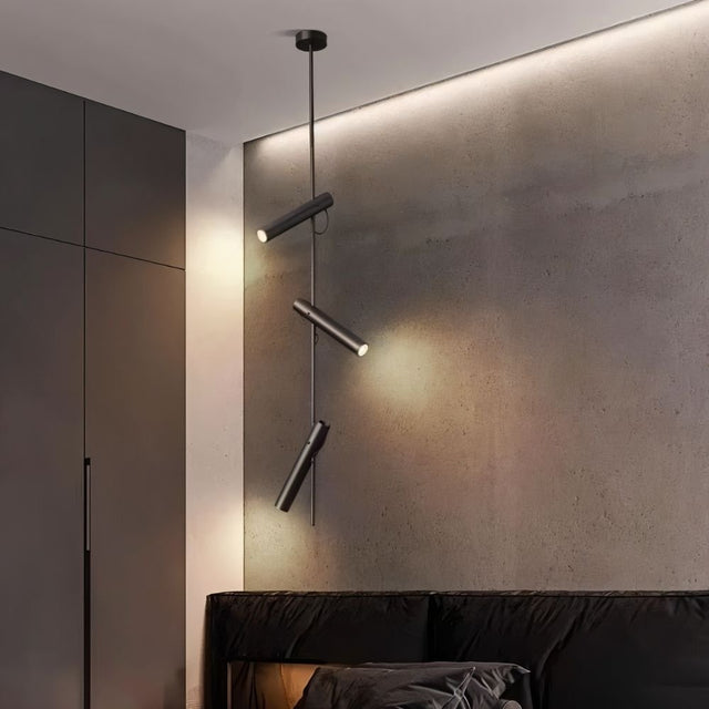 "A modern black stainless steel pendant light with adjustable tubes in a bedroom with a dark headboard."