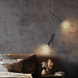 "A modern black stainless steel pendant light with adjustable tubes in a bedroom with a textured wall."