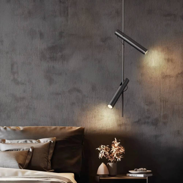 "A modern black stainless steel pendant light with adjustable tubes in a bedroom with a textured wall."