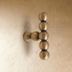 Vintage brass Perla beaded knob with stacked spheres mounted on a cream textured wall