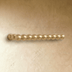 Brass Perla beaded pull bar with aligned spheres mounted on a cream textured wall