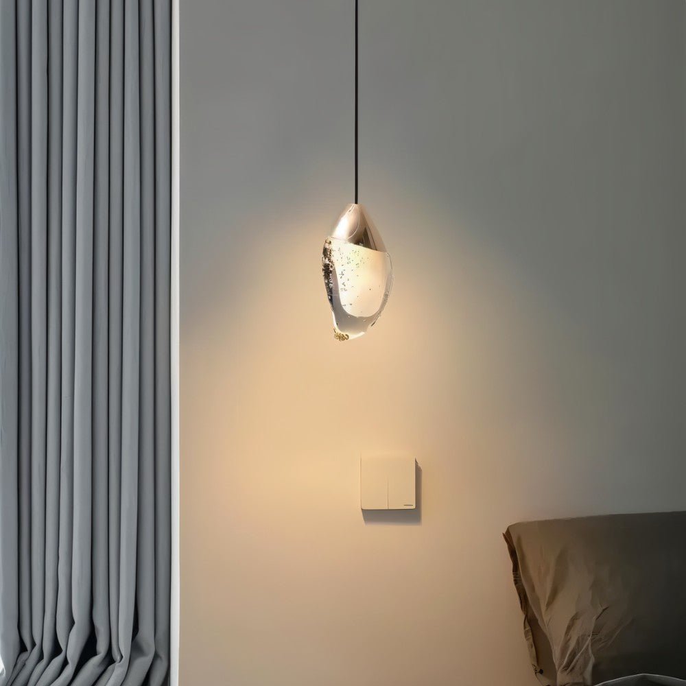 "Modern pendant light with a fluid crystal form and metal top next to a bed in a bedroom."