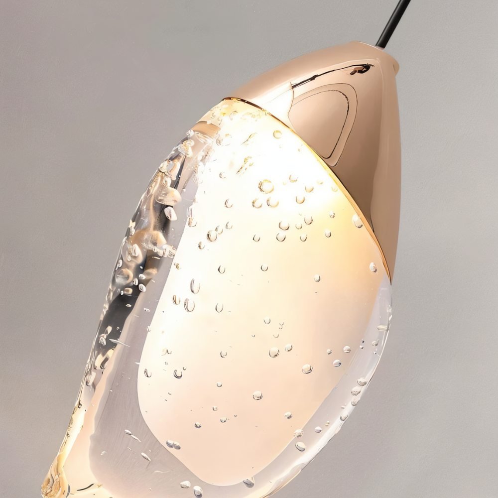 "Close-up detail of a modern pendant light showing a fluid crystal form and metal top."





