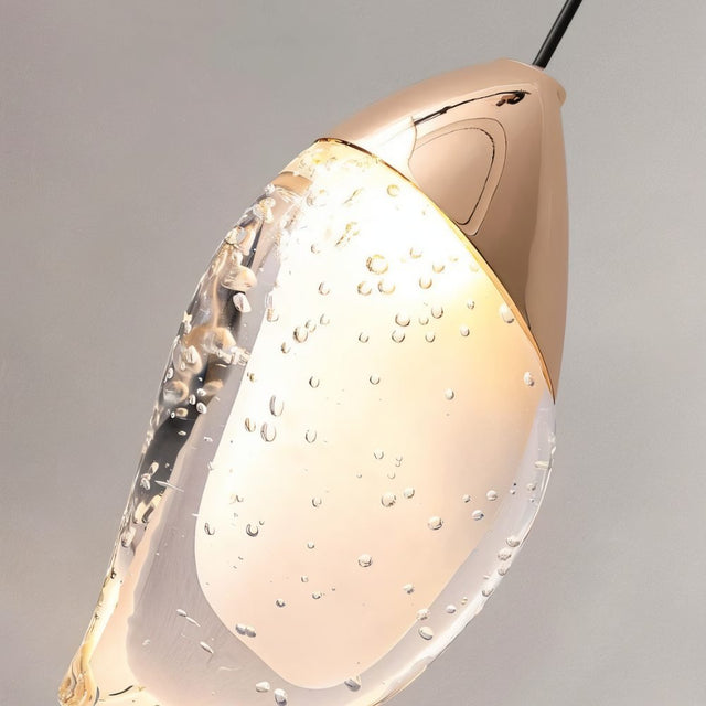 "Close-up detail of a modern pendant light showing a fluid crystal form and metal top."





