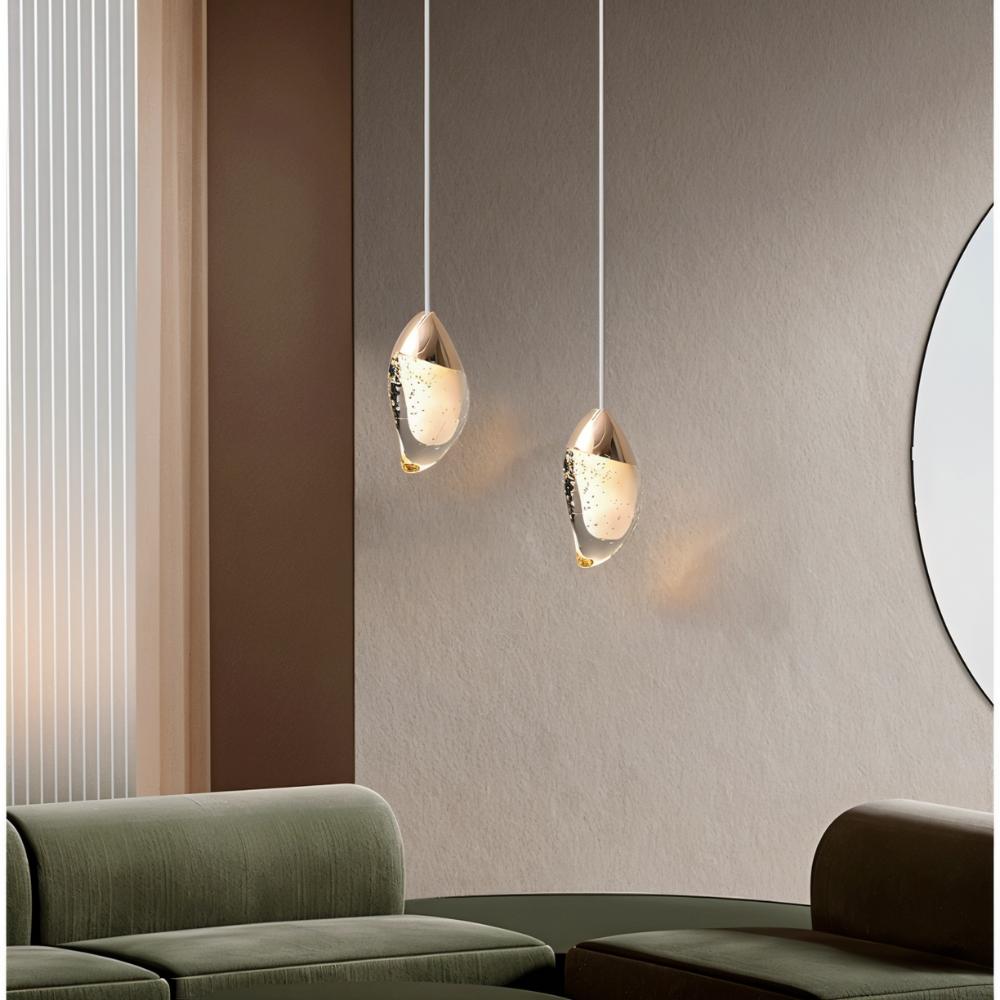  "Pair of modern pendant lights with fluid crystal forms and metal tops in a contemporary living room with a green sofa."
