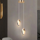 "Pair of modern pendant lights with fluid crystal forms and gold metal tops in a contemporary living room."