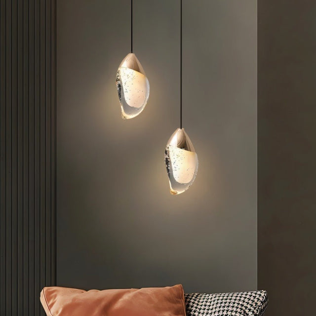 "Pair of modern pendant lights with fluid crystal forms and metal tops in a contemporary living room."